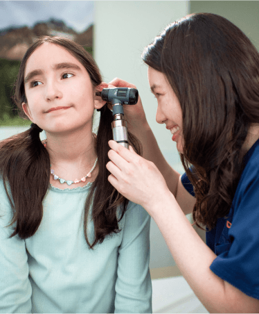 Optum WA doctor examining a young girl's ear with an otoscope during an ENT check-up.