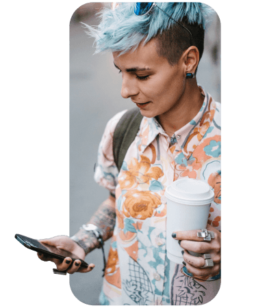Stylish person with short blue hair and tattoos checking their smartphone