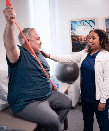 Medical expert assisting a patient with a resistance band exercise