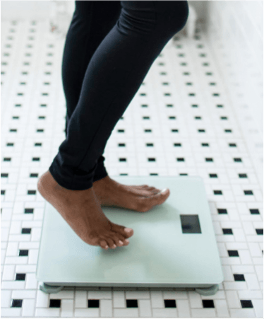 Person stepping onto a digital scale for weight management