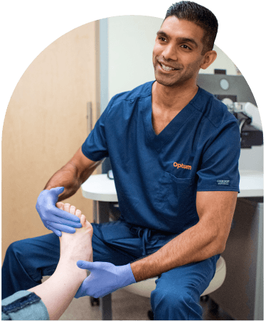 Podiatrist in blue scrubs at Optum WA examining a patient's foot