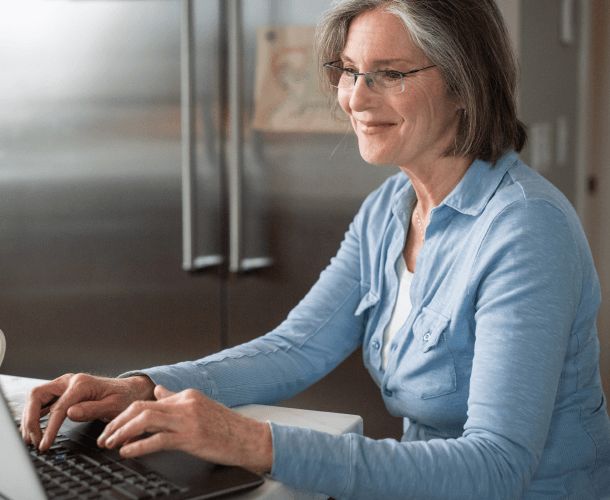 Smiling senior woman using a laptop at home accessing online healthcare services at Optum WA.